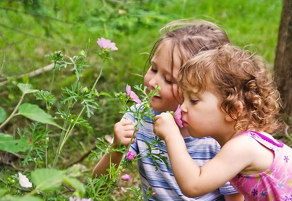 Zwei Mädchen, die an einer Blume schnuppern